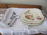 Stack of three patterned plates with hardware components on lace cloth