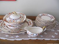 Stacked "Indian Tree" pattern dinnerware pieces including platters, bowls with lid, gravy boat and assorted plates