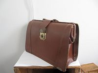Front and side view of brown leather attache case with clasp and handle visible