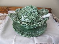Cabbage-form soup tureen with lid on underplate and ladle inserted