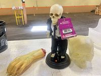 Skeleton figure with tag, severed hand, gel skull on table