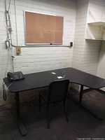 Overall view of L-shaped desk, chair, corkboard on wall