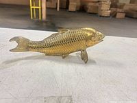 Full left-side view of brass fish figurine on tabletop