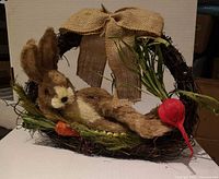 Front view of wreath showing bunny, burlap bow, vegetables and greenery