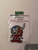 Front of sealed package showing Embro Bof iron-on patch with demon/skull design
