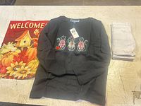 Lot overview showing sweatshirt, garden flag, stack of white napkins