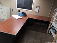 Overall view of L-shaped desk showing cherry laminate top and black base