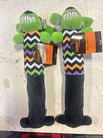 Front view of both Multipet Halloween plush dog toys with tags attached