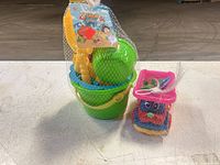 Full view of net-bagged beach toy set showing bucket, tools, truck