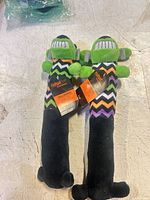Front view of two identical Multipet Halloween plush dog toys with tags attached
