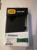 Front of boxed OtterBox Defender Series case showing model window and partial accessory view
