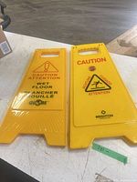 Front view of both yellow foldable caution signs showing logos and multilingual text