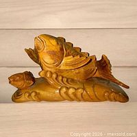 Front view of hand carved wood koi fish on wave base