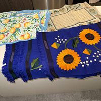 Three placemat designs stacked: lemon print, gardening tools, sunflower woven