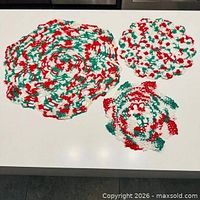 Overview of three circular crochet doilies in Christmas colours on tabletop