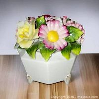 Front view of porcelain floral figurine showing yellow rose and pink daisy on white hexagonal base