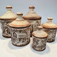front view of all five ceramic canisters with lids showing relief scenes