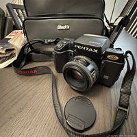 Pentax SF1 camera with lens, cap, strap and Black’s bag visible