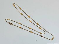 Full view of 18K gold necklace laid out to show length and station pattern