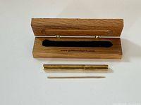Gold toothpick, brass case and open wooden box with velvet interior