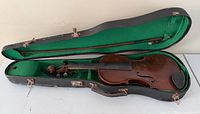 Violin in open case showing interior and exterior damage