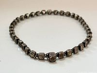 Full view of necklace coiled showing linked square paste stones