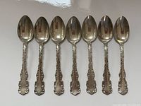 All seven matching sterling silver spoons aligned bowl-up