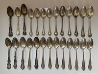 Full set of 26 sterling silver spoons arranged in rows