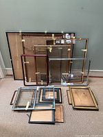 Group of seventeen assorted frames arranged on carpet and leaning against wall