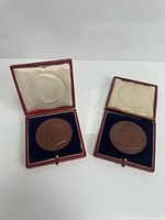 Two open red cases displaying bronze medals