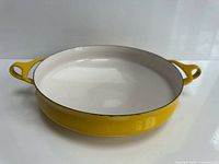 Yellow Dansk Kobenstyle paella pan side profile showing white interior and twin handles