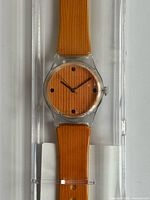 Front view of watch showing wood-grain dial and strap inside clear box