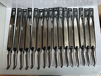 Sixteen packaged Furi Pro knives lined up blade to handle