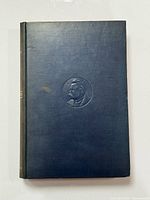 Front cover of navy cloth hardcover book with embossed profile on centre