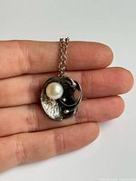 Pendant close-up showing pearl and textured silver