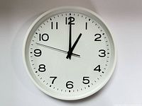 Front view of white Muji wall clock showing numbers and hands