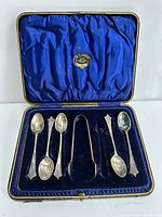 Open case displaying five teaspoons and sugar tongs