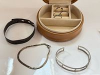 Overview of three bracelets, open leather case and rings