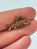 Pendant on fingertips displaying overall size, articulation and enamel color