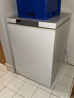 Front and left side view of white upright freezer with power cord visible