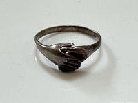 Front view of sterling ring showing clasped hands design