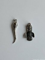 Front view of both sterling silver pendants: cornicello horn and totem pole charm