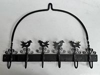 Front view of wrought iron rack showing bird silhouettes, scrollwork, and hooks
