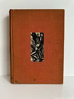 Front cover of orange cloth hardcover with inset woodcut illustration