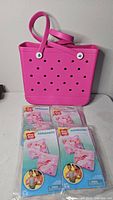 Pink perforated beach tote and four sealed Play Day armband packages