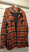 Front view of Carhartt plaid flannel shirt jacket on hanger