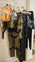 Three costumes on hangers: Tonka Chuck backpack, Halo Master Chief suit, pixel-pattern suit