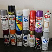 Full view of twelve assorted spray paint cans stacked in two rows.