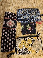 Four Vera Bradley wallets and coin purse on woven mat