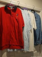 Five tops hanging on hangers showing variety